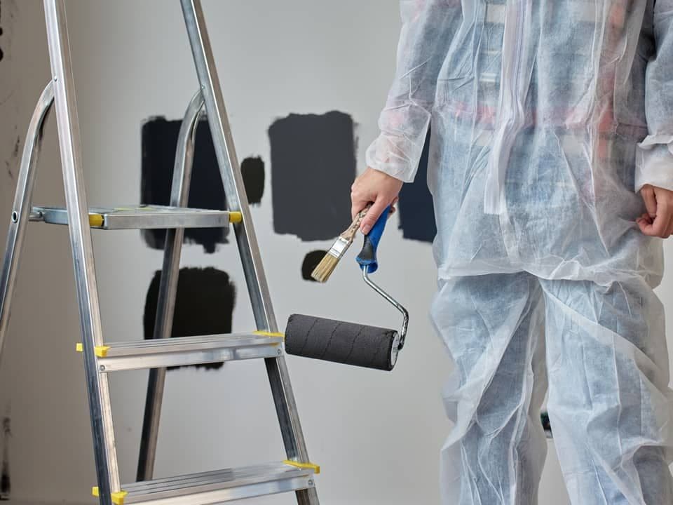 Painter with roller and brush preparing an interior wall for a new coat